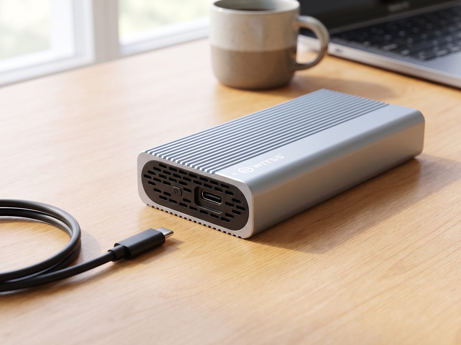 Switss® USB4 M.2 behuizing op een bureau, USB-C poort en heatsink-ribbels in detail met losse USB-C kabel