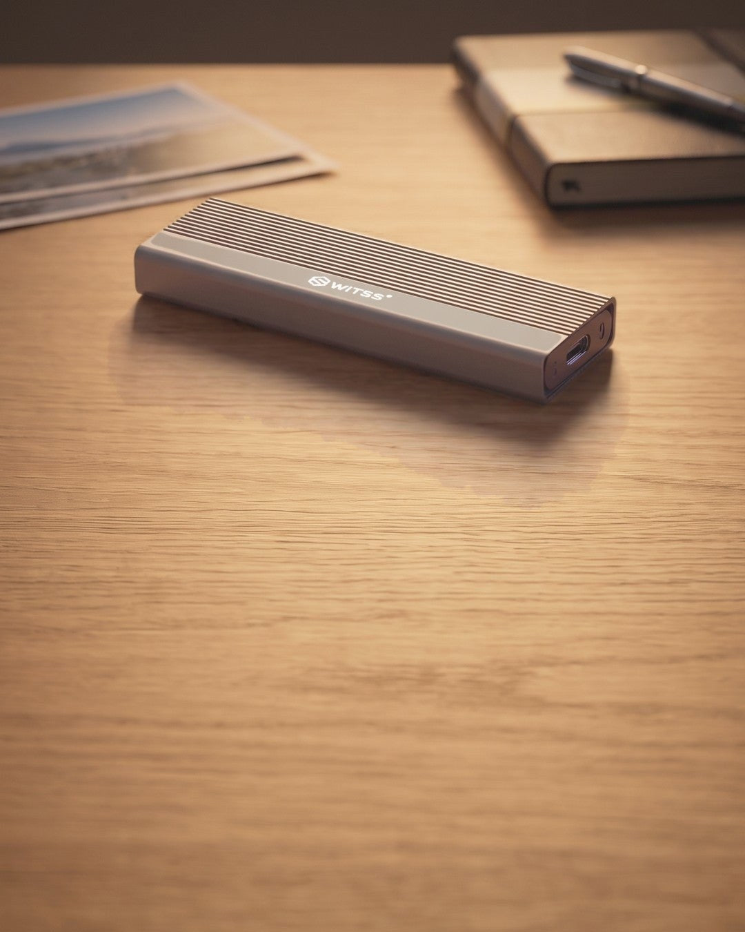 Boîtier SSD M.2 Switss® sur un bureau à côté de photos de famille imprimées
