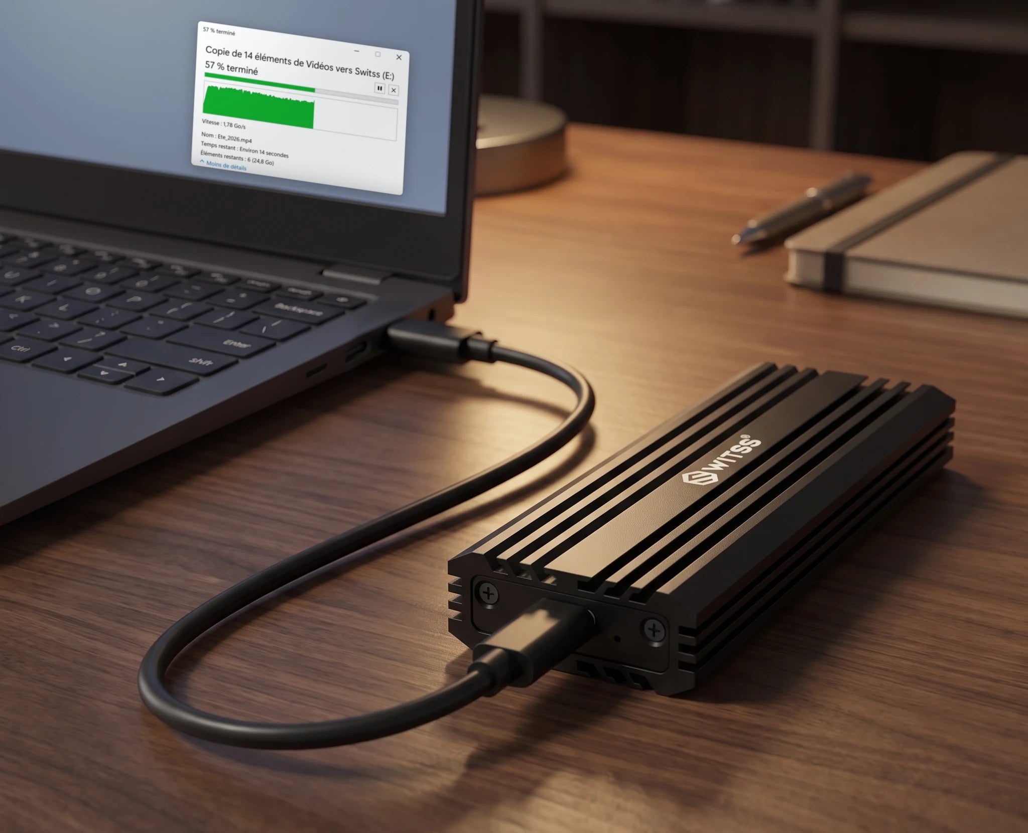 Le boîtier M.2 Switss relié à un ordinateur portable par le câble USB-C, avec une copie de fichiers vers le disque en cours à l’écran