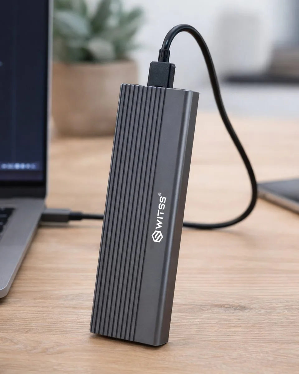 Switss M.2 SSD-behuizing rechtop op een bureau, met de kabel aangesloten op een laptop