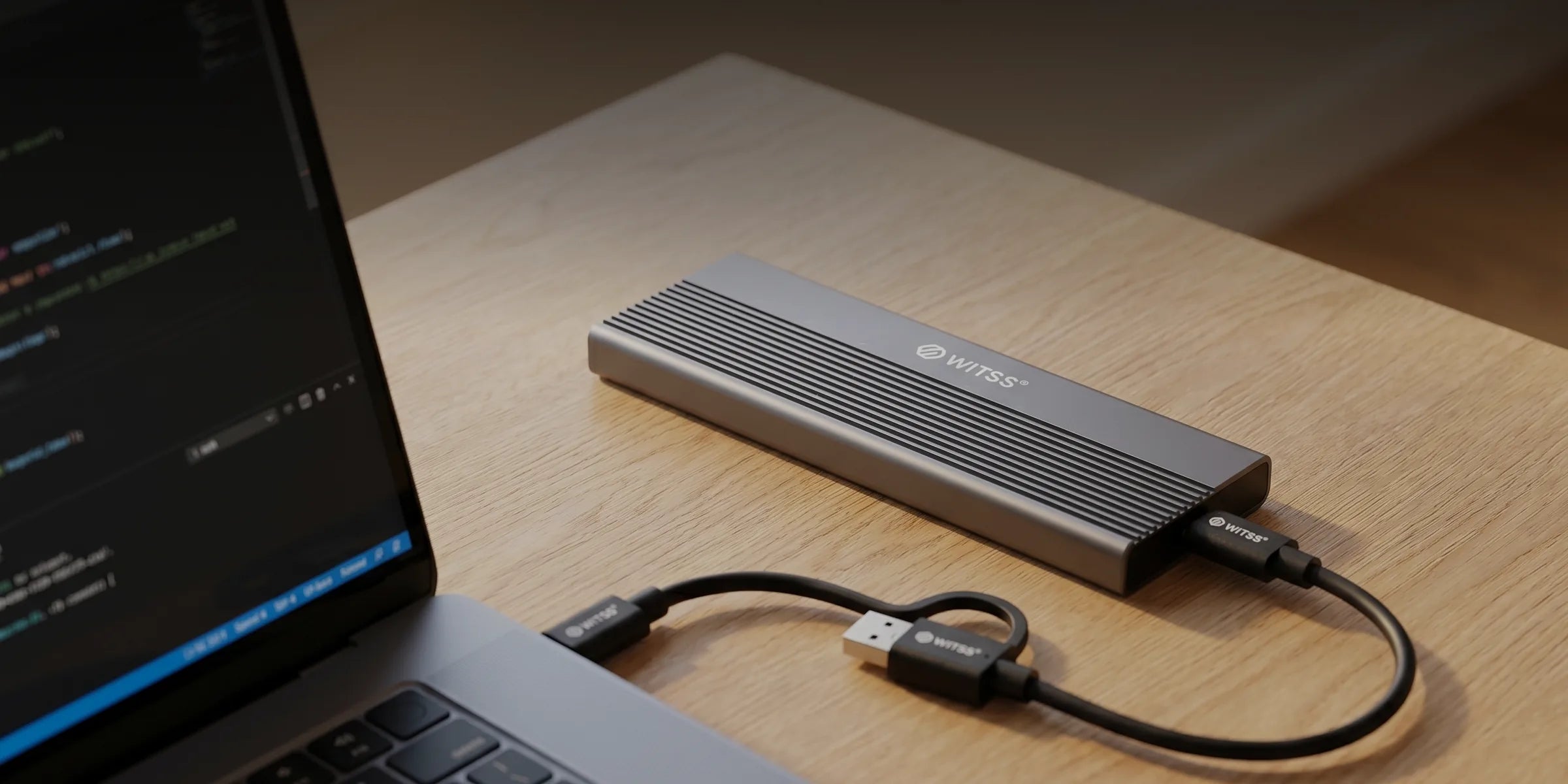 De M.2-behuizing op een houten bureau, met de USB-C-kabel aangesloten op een laptop, in avondlicht