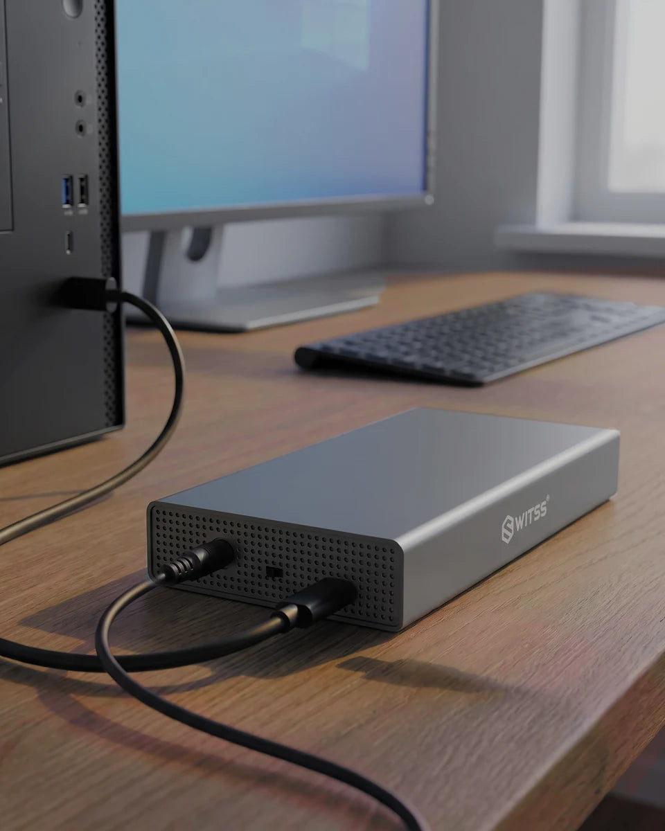 Le boîtier Switss 3,5 pouces sur un bureau en bois, câble USB relié à un PC et adaptateur secteur branché
