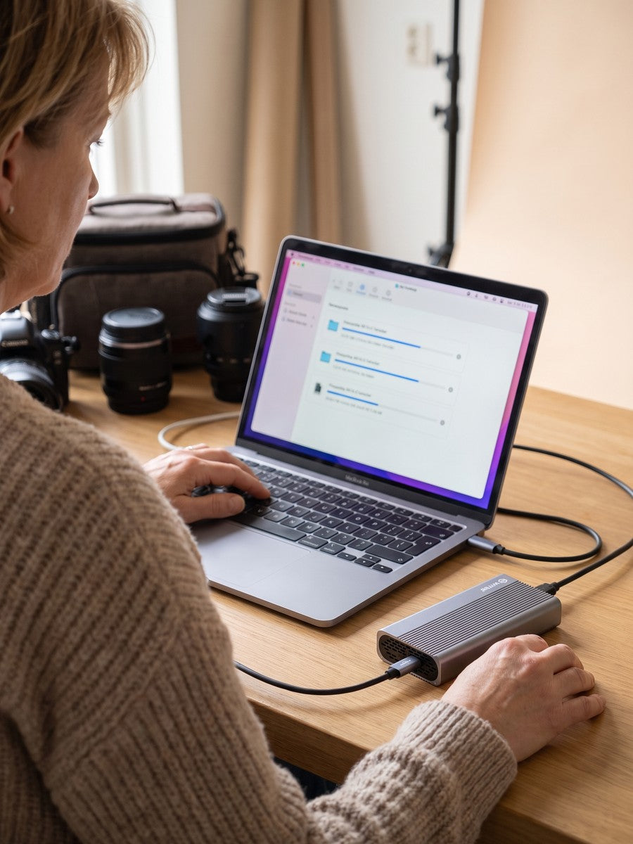 Vrouw zet videobestanden over, laptop met voortgangslijst en een camera op tafel